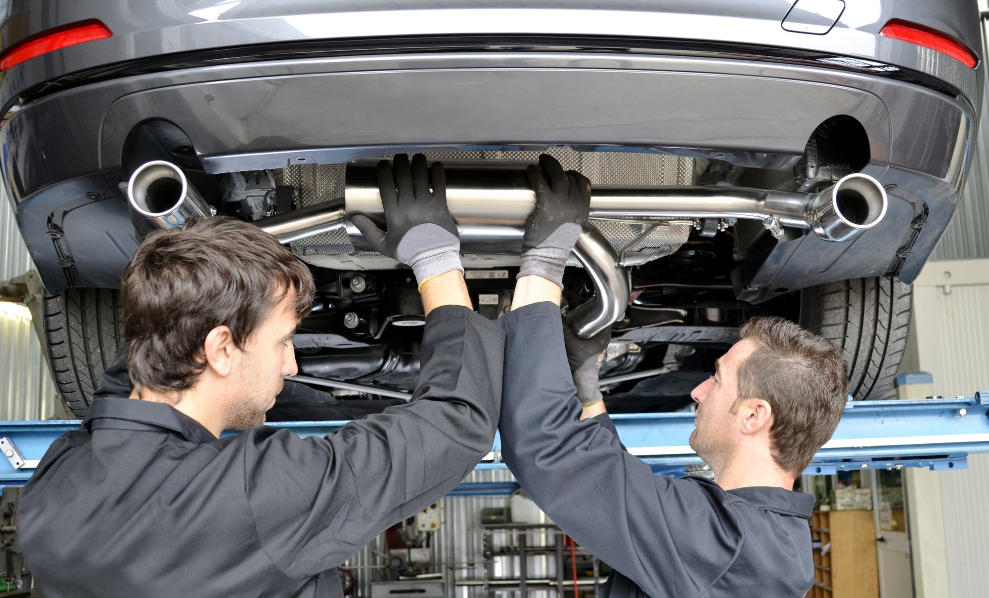 car mechanics installing exhaust system